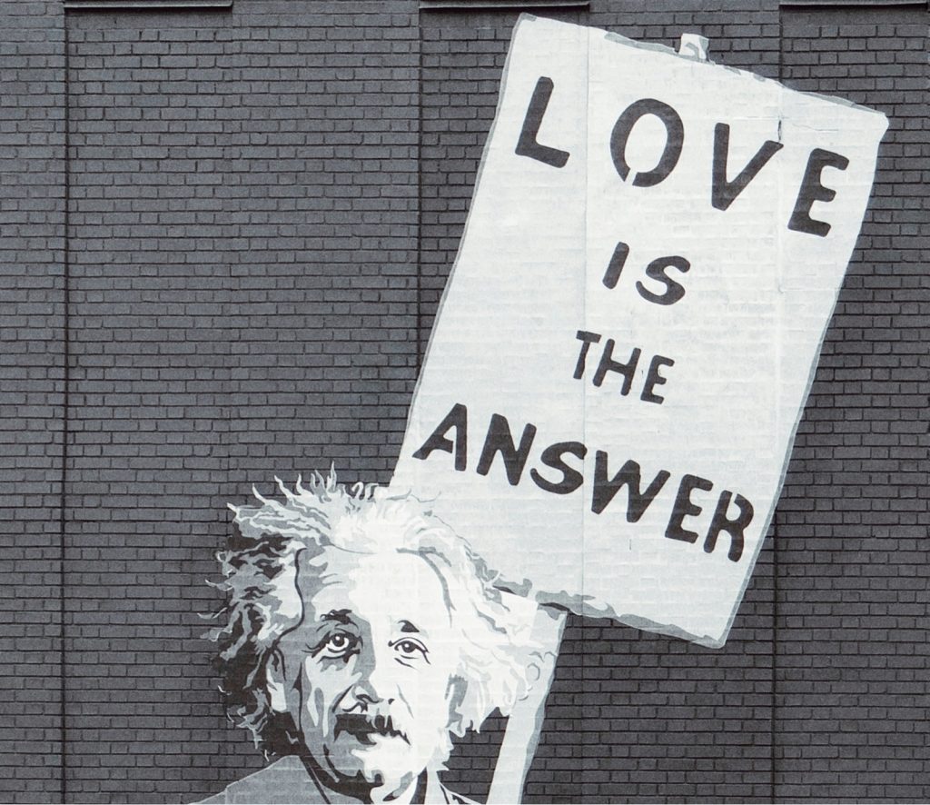 A charcoal sketch of Albert Einstein with a sign that reads Love Is the Answer